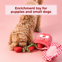 Small dog sniffing out treats from the strawberries of the opened toy. Text: Enrichment toy for puppies and small dogs